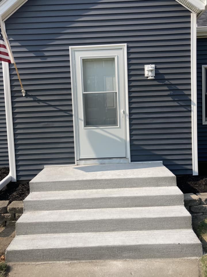 Concrete stairs to the front door with new vinyl siding installed in Durant, Iowa