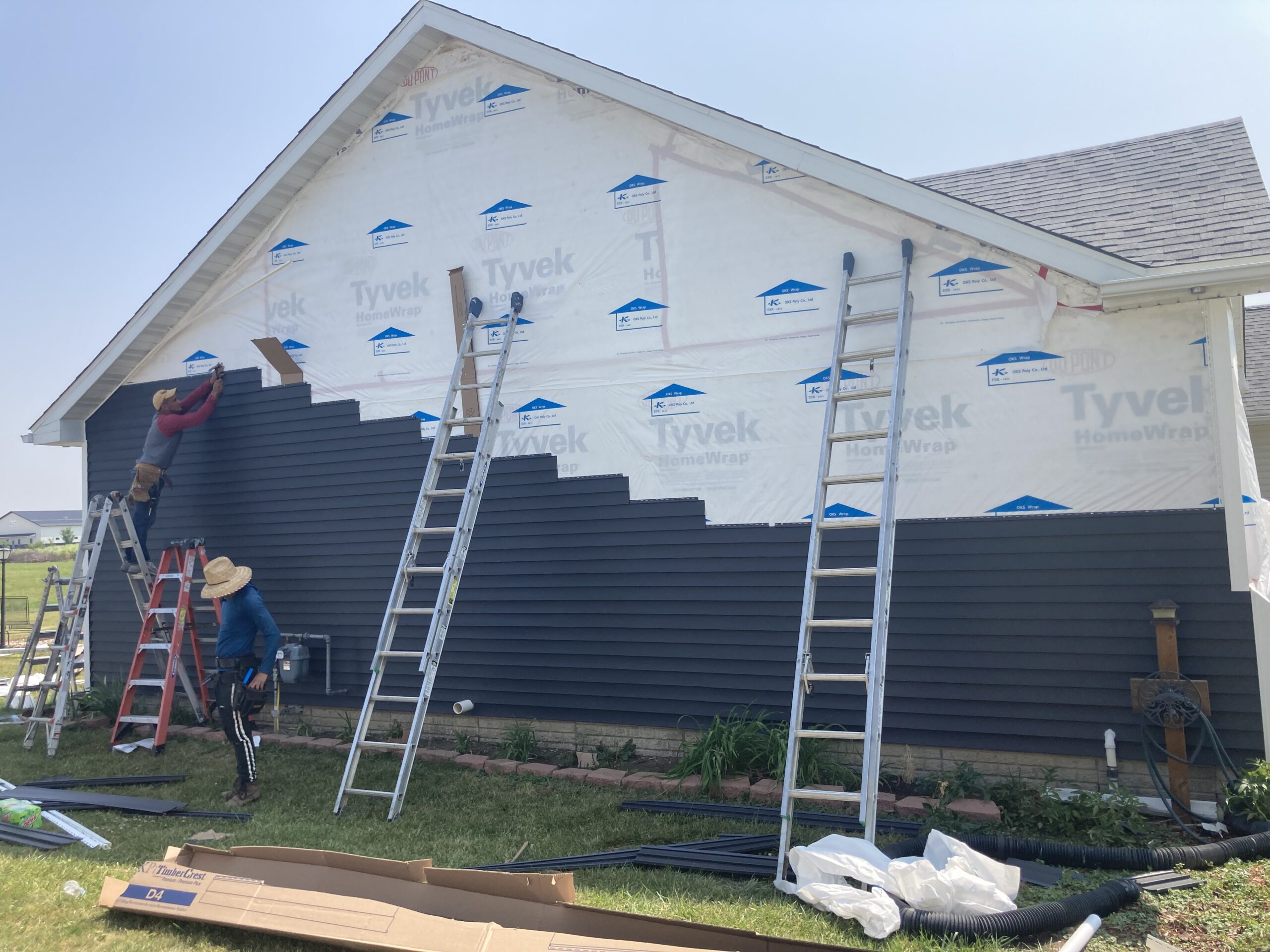 Crew installing vinyl siding over oks poly house wrap on a home in West Liberty, Iowa
