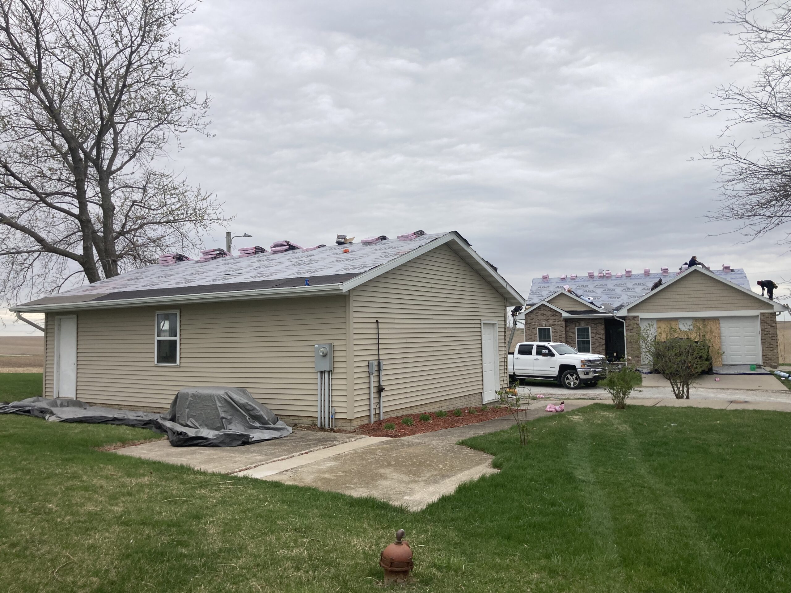 Crews working on the garage and home as they expertly replace the storm damaged roof with durable asphalt shingles