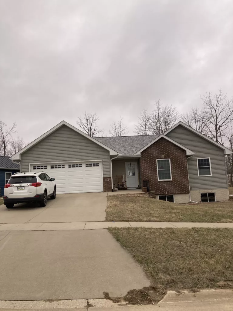 Finished view of replaced siding, shingles, gutters, and downspouts on a home in Tipton, Iowa (front)