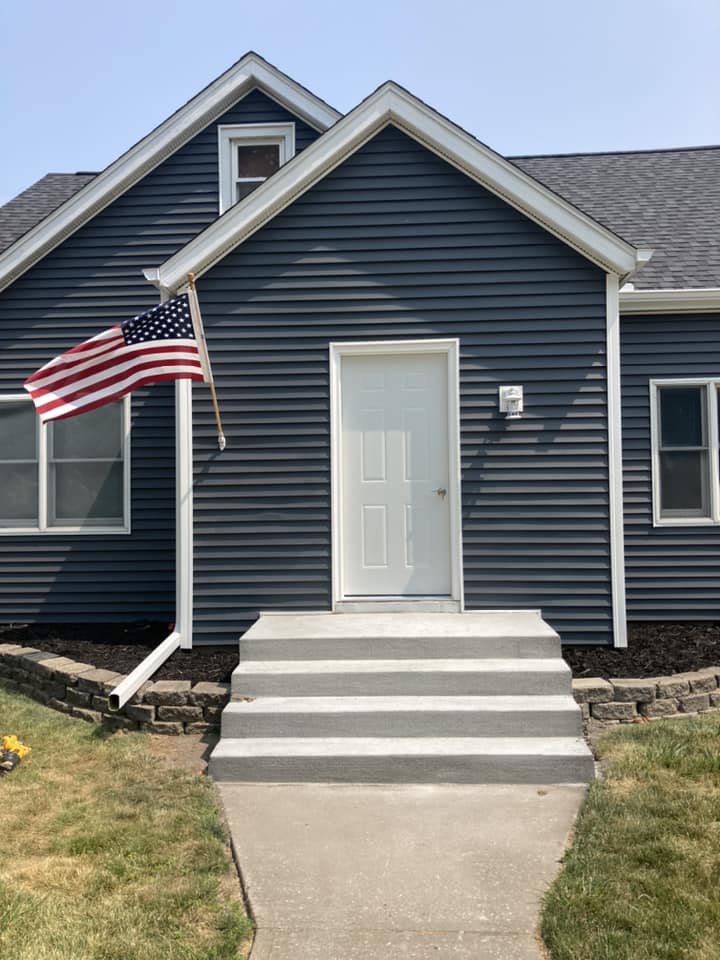 Finished vinyl siding installed on the front with new concrete stairs in Durant, Iowa