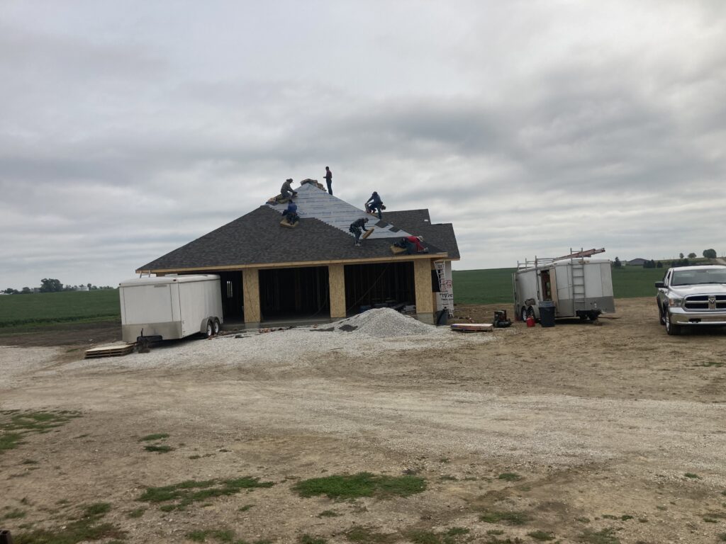 Hernandez KD Construction Crew installing shingles on new home construction in Marion, Iowa over the garage