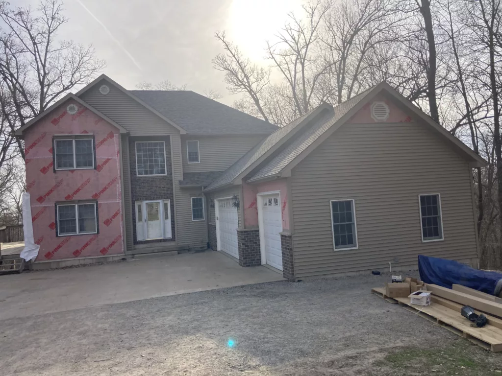Front of home with wind and hail damaged siding removed in Tipton, Iowa