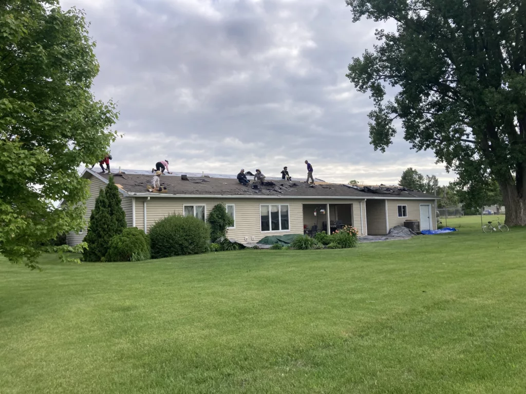 Back of the home - Crew working on taking off the damaged and missing asphalt shingles due to wind and hail damage roof in Stanwood, Iowa