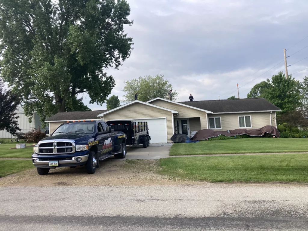 Crew working on taking off the damaged and missing asphalt shingles due to wind and hail damage roof in Stanwood, Iowa