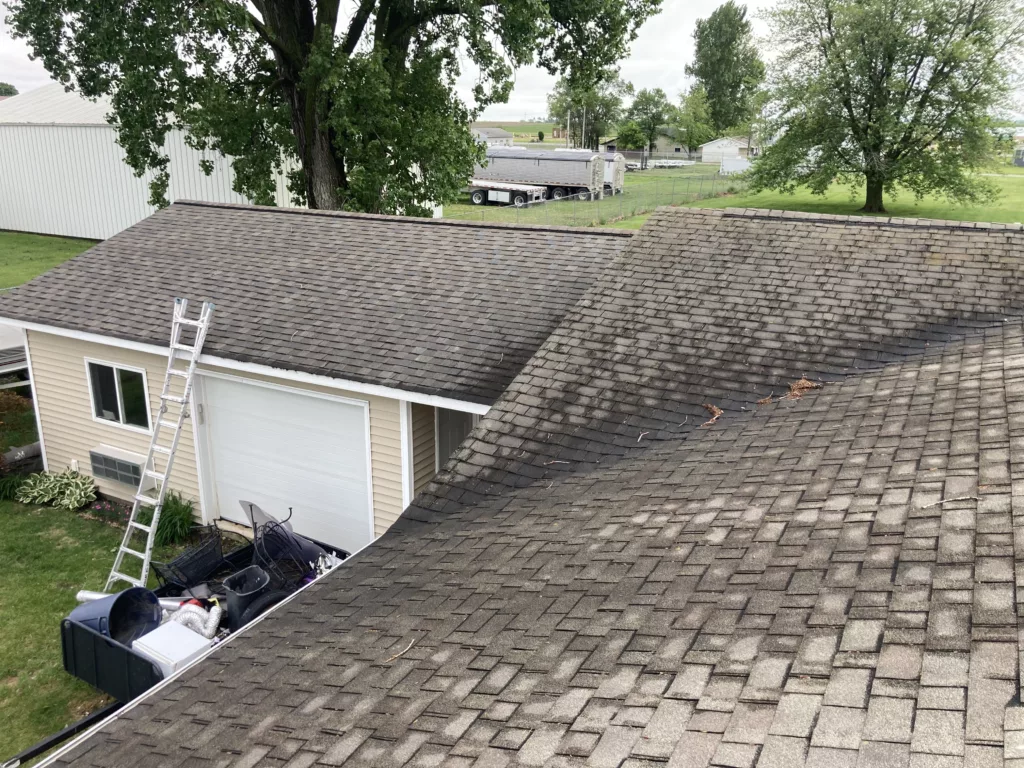 Original roof with missing asphalt shingles due to wind and hail damage roof in Stanwood, Iowa. It never dries out.